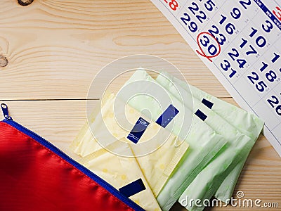 The sanitary napkins were stacked on a wooden floor and a calendar marked with red circles around 30 Stock Photo