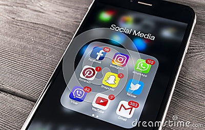 Apple iPhone 7 on wooden table with icons of social media facebook, instagram, twitter, snapchat application on screen. Smartphone Editorial Stock Photo