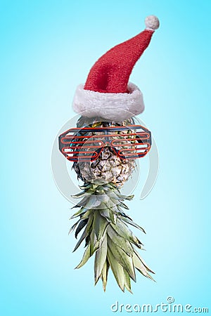 Santa ananas. Funky pop art minimal christmas in summer concept. Funny pineapple with sunglasses and santa claus hat on bright Stock Photo