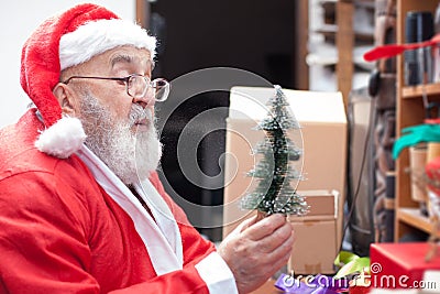 Santa Claus blowing snow at tiny christmas tree Stock Photo