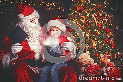 Santa Claus and child girl with bright magical gift in Christmas Stock Photo