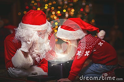 Santa Claus and child girl with bright magical gift in Christmas Stock Photo