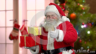 Santa Claus holding presents with thumb up. Old bearded Santa holding festive gift boxes. Winter holiday celebration. Christmas season sales stock video Santa Claus holding presents with thumb up. Old bearded Santa holding festive gift boxes. Winter holiday celebration. Christmas season sales stock video