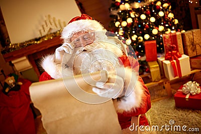 Santa Claus looking at long list with children desire Stock Photo