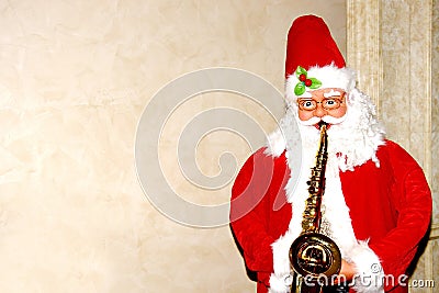 Santa Claus plays the trumpet on a light beige background standing at the side Stock Photo