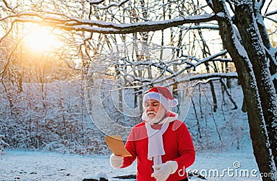 Santa Claus read wish list and walk in the snowy christmas woodland. Stock Photo