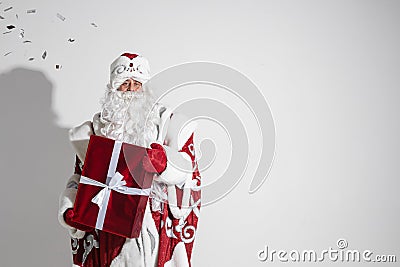 Santa Claus with red xmas gift posing in studio, elderly male with christmas present, copy space for holiday advertising Stock Photo