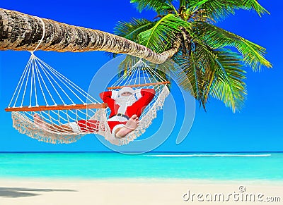 Santa Claus relax in hammock at island palm tropical beach Stock Photo