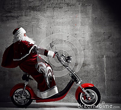 Santa Claus ride motorcycle bicycle scooter with bag full of present gifts with text copy space. New year and Merry Christmas Stock Photo