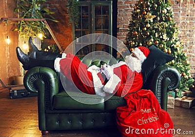 Santa Claus sleeping at home near Christmas tree Stock Photo