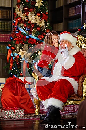 Santa Claus tells a funny story to a cute little girl on the holiday of Christmas. Stock Photo