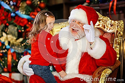 Santa Claus tells a funny story to a cute little girl on the holiday of Christmas. Stock Photo