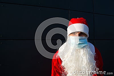 Santa Claus with white beard in red coat in a medical mask. Christmas in the coronavirus pandemic, seasonal diseases, SARS and pne Stock Photo