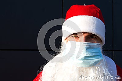 Santa Claus with white beard in red coat in a medical mask. Christmas in the coronavirus pandemic, seasonal diseases, SARS and pne Stock Photo