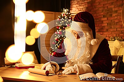 Santa Claus writing letter at table indoors Stock Photo