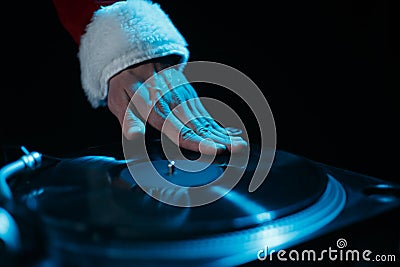 Santa DJ scratches vinyl record on turntable. Club disk jokey in red Christmas clothes plays music Stock Photo