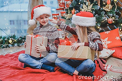 Santa-dressed children are teasing one another, competing whose present is better. Stock Photo