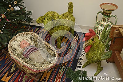 Santa gifts made of straw toys doll in a cradle, sheep and rooster placed by Christmas tree before New Year. Kyiv, Ukraine Stock Photo