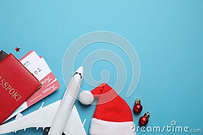 Santa hat, toy airplane, passports with airline tickets and space for text on blue background, flat lay. Christmas vacation Stock Photo