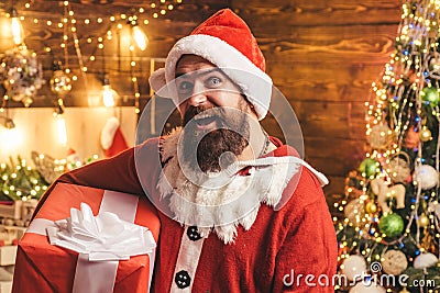 Santa man holding gift. Hipster man, bearded Santa celebrate Thanksgiving day and Christmas. Hipster in red Santa hat Stock Photo