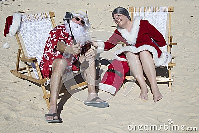 Santa and Mrs Claus taking selfie on beach Stock Photo