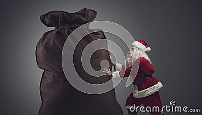 Santa pushing a huge sack with gifts Stock Photo