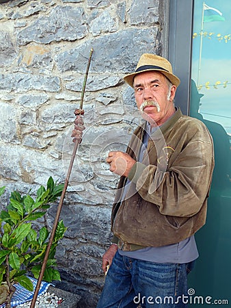 An old Portuguese man with mustache enjoying traditional grilled beef on bay laurel skewers Editorial Stock Photo