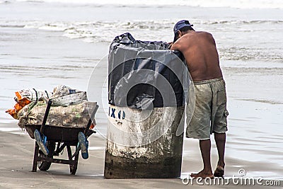 Man looks for aluminum cans for recycling in a trash bin Editorial Stock Photo