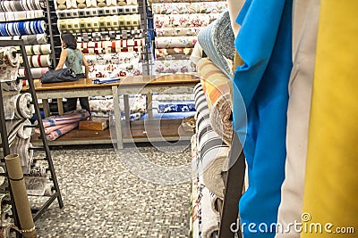 people inside of traditional fabric store with stacks of colorful textiles Editorial Stock Photo