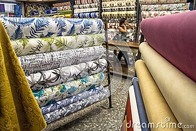 people inside of traditional fabric store with stacks of colorful textiles Editorial Stock Photo