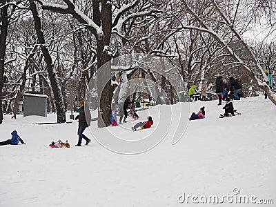 Saratov, Russia - Jan,2022: little girl rides on an ice slide next to older children in the city park where children Editorial Stock Photo