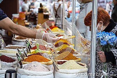 Saratov, Russia - 10/04/2020: Sale of various natural fragrant Asian Indian spices in bags in an oriental bazaar, a man`s hand in Editorial Stock Photo