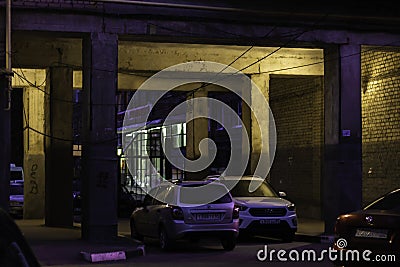 Cars parked in the arch of the Soviet apartment house in the purple light of the evening Editorial Stock Photo