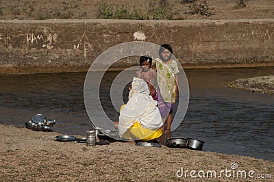 Indian family washing the cooking utensils in the Hiran River. Editorial Stock Photo