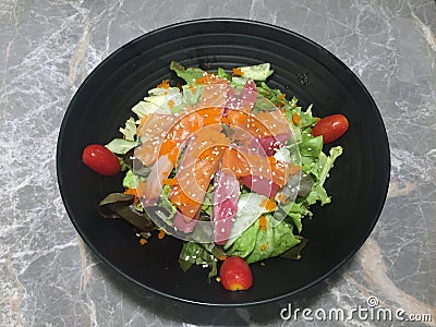 Sashimi salad in the black bowl on the marble table, Raw fish salad and tomato. Stock Photo