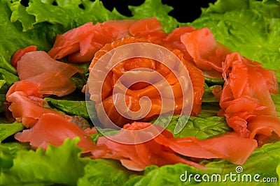 Sashimi syake with salmon slices arranged in form of rose, lemon slices, wasabi and lettuce leaves on a rectangular plate, closeup Stock Photo