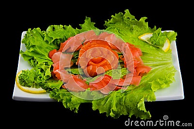 Sashimi syake with salmon slices arranged in form of rose, lemon slices, wasabi and lettuce leaves on a rectangular plate, Stock Photo