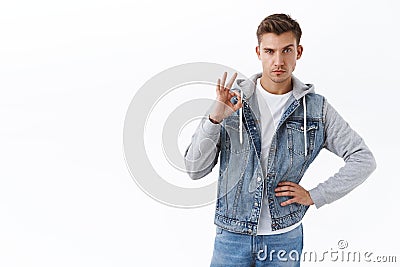 Sassy handsome gay man with blond hair look camera determined and confident, assuring all okay, show OK sign give his Stock Photo