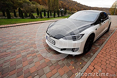 Sataniv, Ukraine - October 23, 2022: Dual color black and white Tesla Model S on pavement at utumn forest Editorial Stock Photo