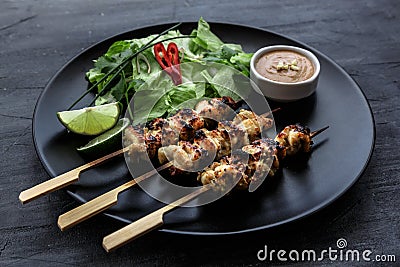 Satay is a Malaysian-style kebab. It served with peanut sauce, slivers of cucumbers and onions. Stock Photo