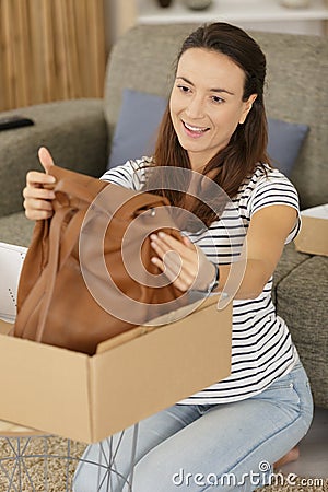 satified woman unpacking new bag from cardboard box Stock Photo