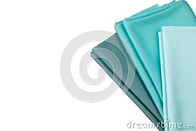 Satin fabrics of blue and green shades of color are spread on the table. The material is folded onto each other. Stock Photo