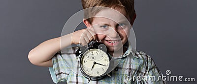 Satirical little kid teasing about time, showing an alarm clock Stock Photo
