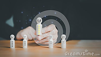 Satisfaction survey concept. User hand chooses a wooden doll with happy smile face. Stock Photo