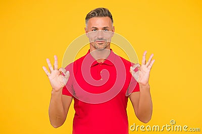 Satisfactory result. Happy man show double OK signs yellow background. Satisfied guy smile with satisfaction. Agreement Stock Photo