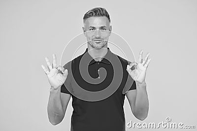 Satisfactory result. Happy man show double OK signs yellow background. Satisfied guy smile with satisfaction. Agreement Stock Photo