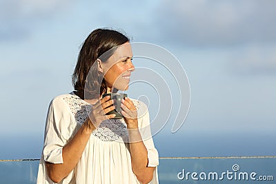 Satisfied adult woman with coffee contemplating on a balcony Stock Photo