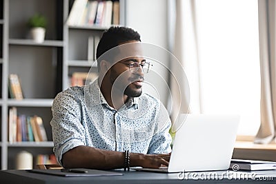 Satisfied African American man wearing glasses looking at computer screen Stock Photo