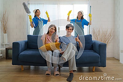 Satisfied Asian homeowner gives a thumbs-up, expressing delight and approval for the exceptional cleaning service provided by the Stock Photo