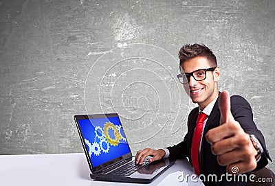 Satisfied business man working on laptop and making ok sign Stock Photo